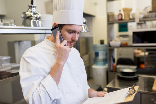 chef calling on smartphone at restaurant kitchen