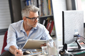 Businessman sitting in office working on tablet